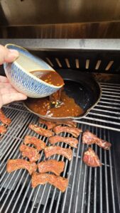 adding sauce to pan while grilling ribs